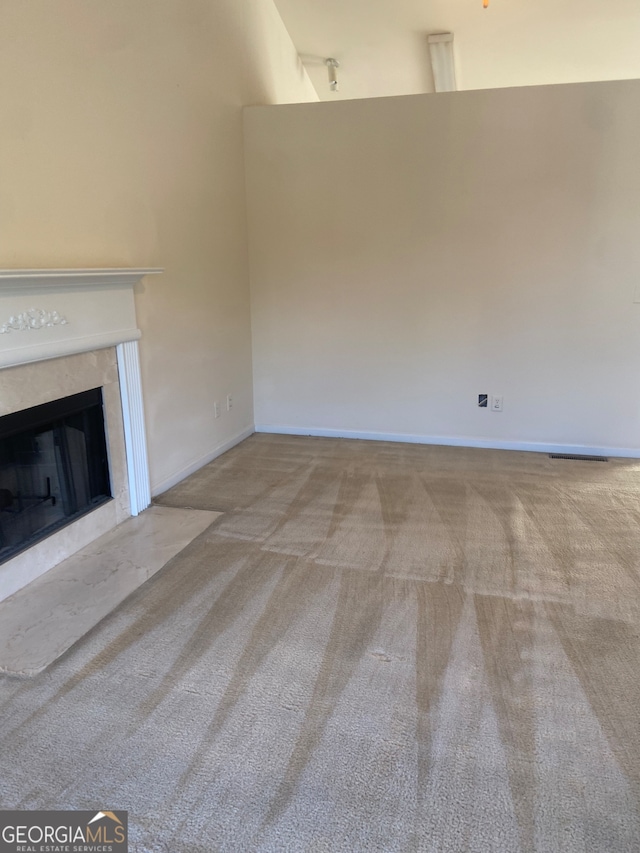 unfurnished living room featuring a towering ceiling, light carpet, and a premium fireplace