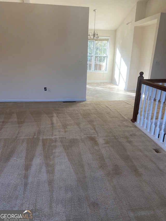 spare room with a notable chandelier and carpet