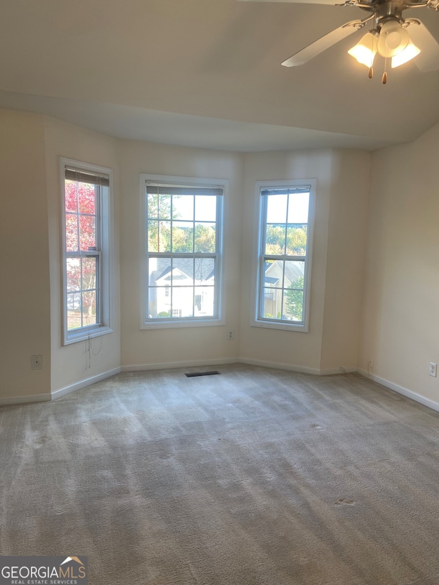 carpeted spare room featuring ceiling fan and a wealth of natural light