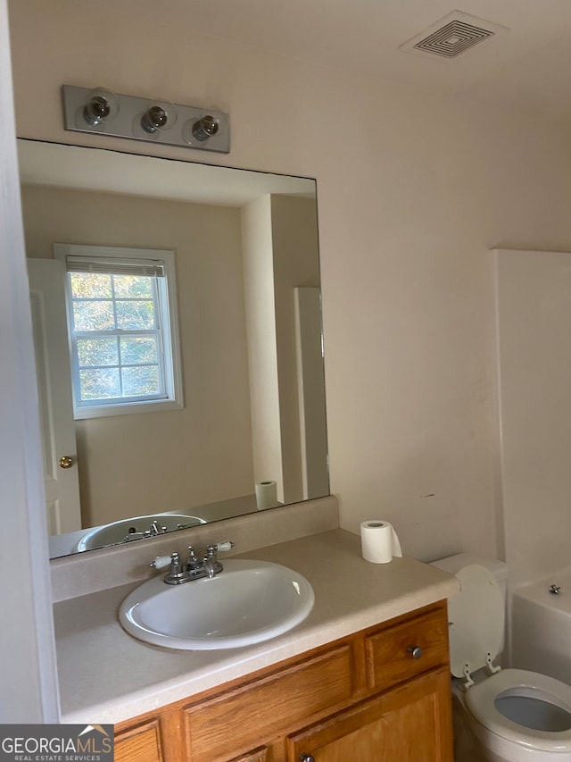 bathroom featuring a tub to relax in, vanity, and toilet