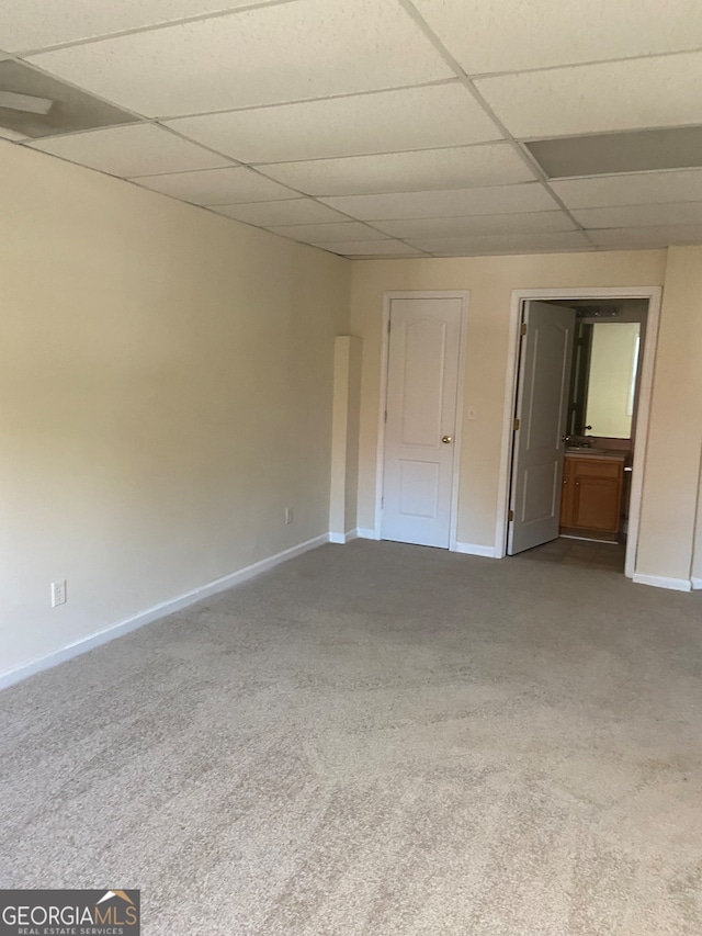 carpeted empty room featuring a drop ceiling