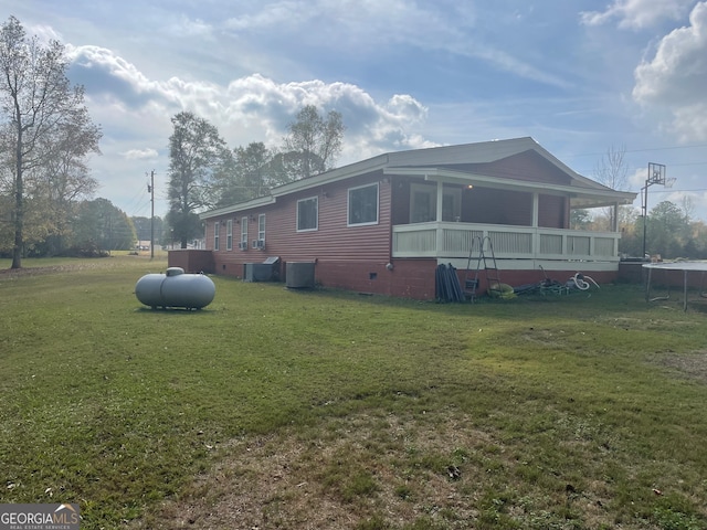 view of side of property with a yard, a sunroom, and central AC unit