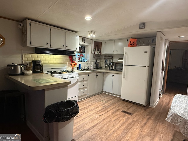 kitchen featuring backsplash, kitchen peninsula, light wood-type flooring, and white appliances