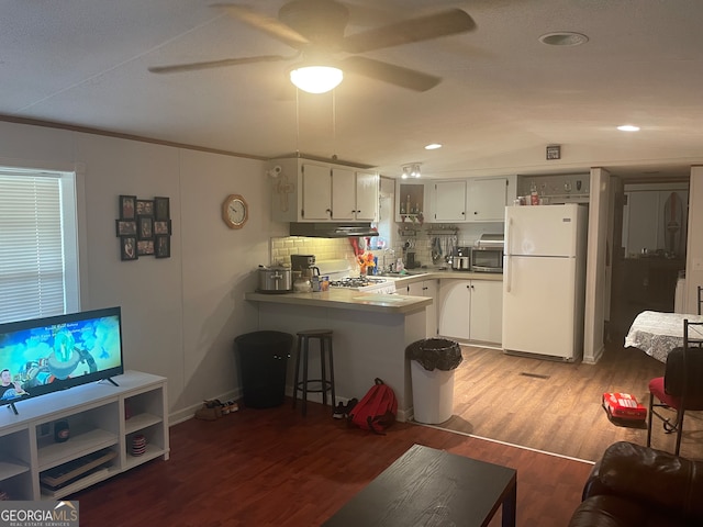 kitchen with kitchen peninsula, backsplash, ceiling fan, white refrigerator, and dark hardwood / wood-style flooring