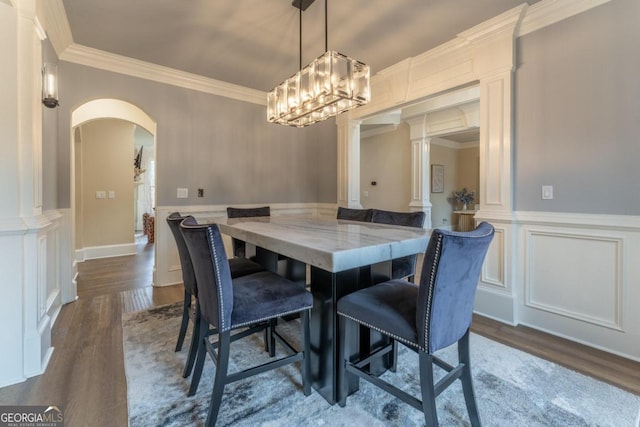 dining area featuring crown molding, wood-type flooring, and ornate columns