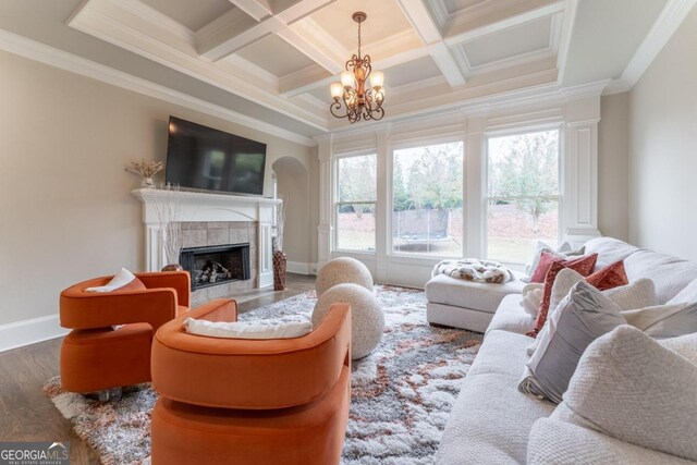 living room featuring hardwood / wood-style flooring, a chandelier, beamed ceiling, a fireplace, and crown molding