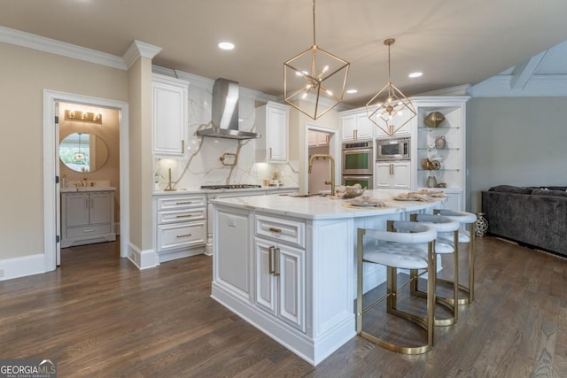 kitchen with white cabinets, a kitchen island with sink, dark wood-type flooring, wall chimney exhaust hood, and stainless steel appliances