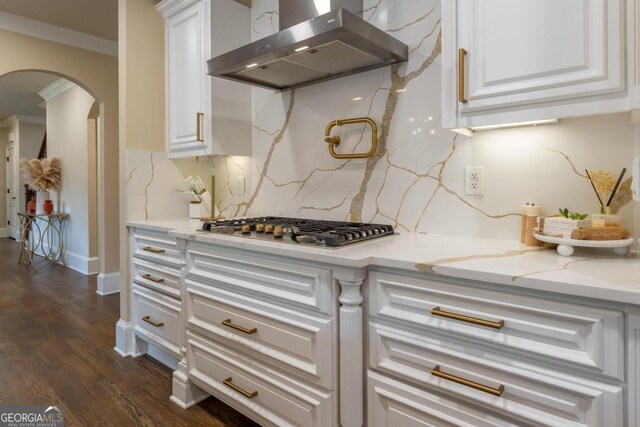 kitchen with dark hardwood / wood-style flooring, stainless steel gas stovetop, range hood, crown molding, and light stone counters