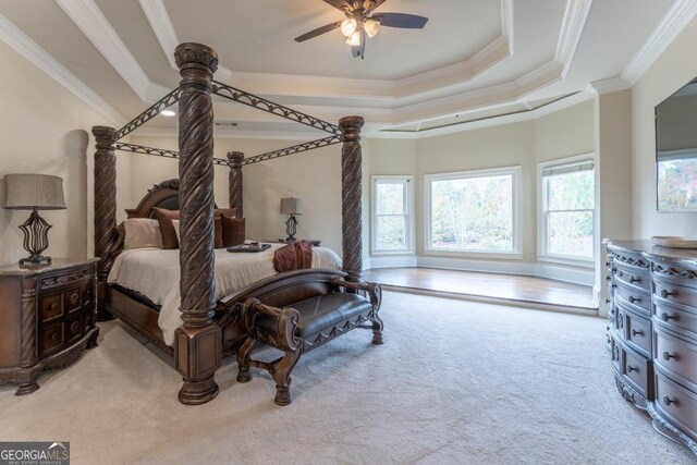 bedroom featuring ornamental molding, a tray ceiling, and light colored carpet