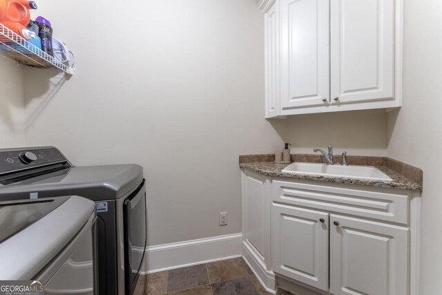 laundry area with sink, washing machine and clothes dryer, and cabinets