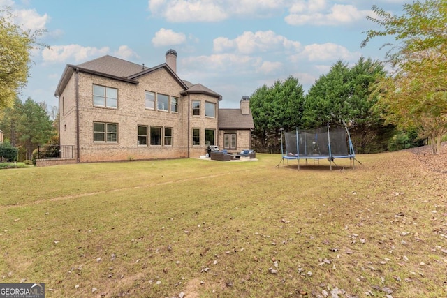 back of house featuring a yard, a trampoline, and a patio