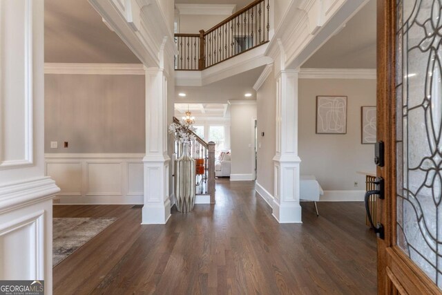 entryway with dark wood-type flooring, crown molding, and decorative columns