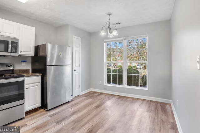 kitchen with white cabinetry, stainless steel appliances, light hardwood / wood-style floors, and decorative light fixtures