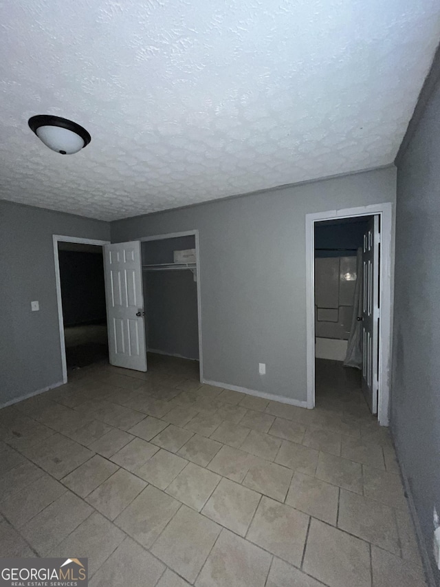 121-123 E King Ave, Kingsland, GA 31548 - unfurnished bedroom with a textured ceiling, a closet, light tile patterned flooring, and baseboards