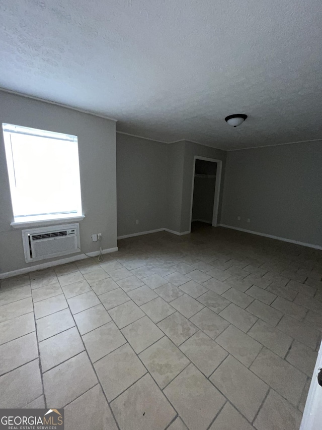 121-123 E King Ave, Kingsland, GA 31548 - empty room featuring a textured ceiling, baseboards, light tile patterned floors, and a wall mounted air conditioner