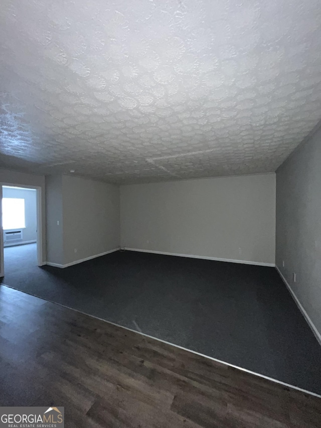 121-123 E King Ave, Kingsland, GA 31548 - unfurnished room featuring baseboards, dark wood-type flooring, and a textured ceiling