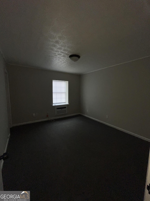 121-123 E King Ave, Kingsland, GA 31548 - spare room with dark carpet, baseboards, a wall mounted air conditioner, and a textured ceiling