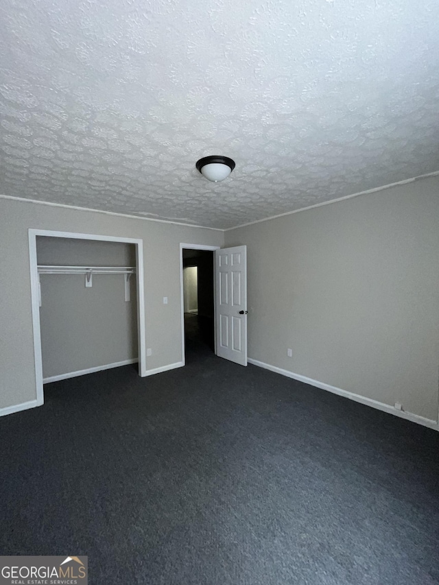 121-123 E King Ave, Kingsland, GA 31548 - unfurnished bedroom featuring a textured ceiling, baseboards, a closet, and dark carpet