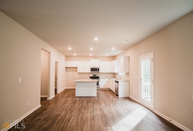 kitchen with appliances with stainless steel finishes, a center island, hardwood / wood-style floors, and white cabinets