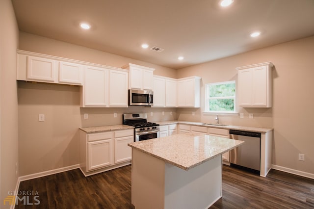 kitchen with stainless steel appliances, dark hardwood / wood-style flooring, a kitchen island, and white cabinets