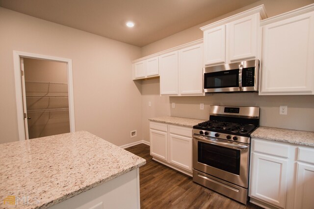 kitchen featuring appliances with stainless steel finishes, light stone counters, and white cabinetry