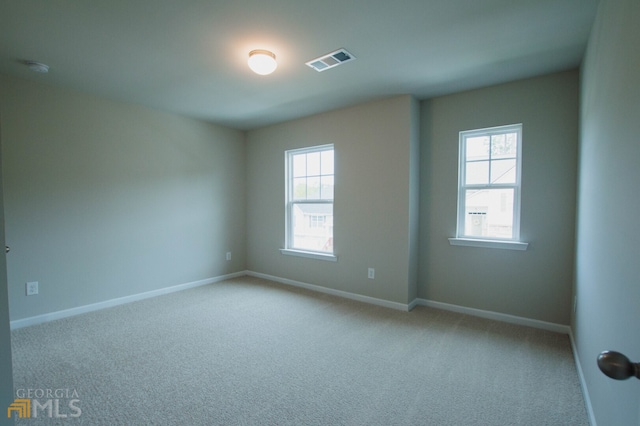 spare room with plenty of natural light and light colored carpet