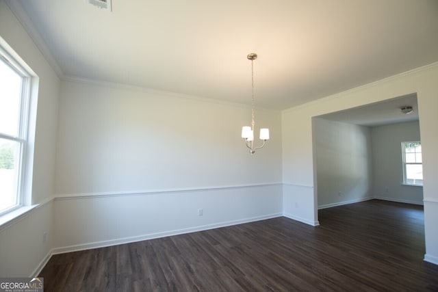 spare room featuring crown molding, an inviting chandelier, plenty of natural light, and dark hardwood / wood-style floors