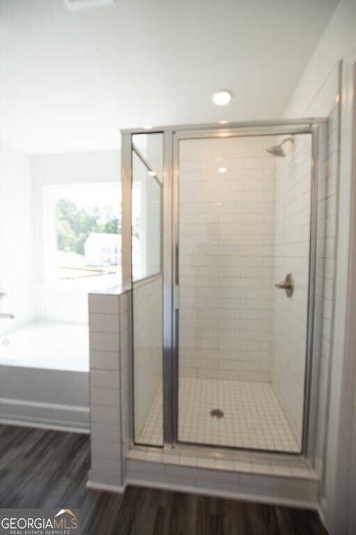 bathroom featuring plus walk in shower and wood-type flooring