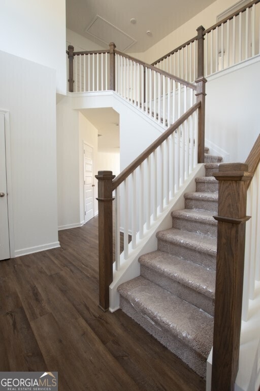 staircase featuring a towering ceiling and hardwood / wood-style floors