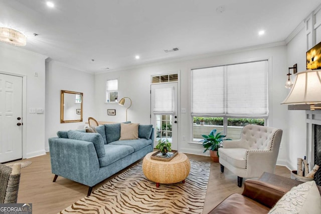 living room with a wealth of natural light, crown molding, and light hardwood / wood-style floors