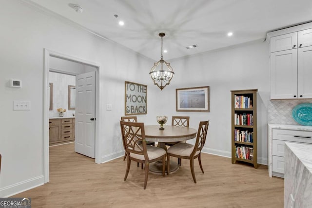 dining area with a notable chandelier, light hardwood / wood-style floors, and crown molding