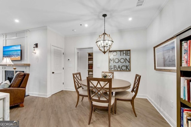 dining area featuring crown molding, a chandelier, and light hardwood / wood-style floors