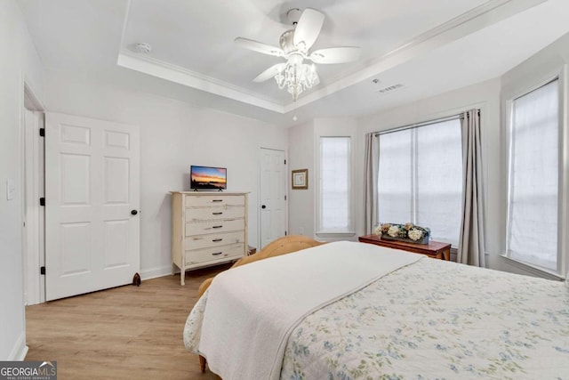 bedroom with a tray ceiling, light hardwood / wood-style flooring, and ceiling fan