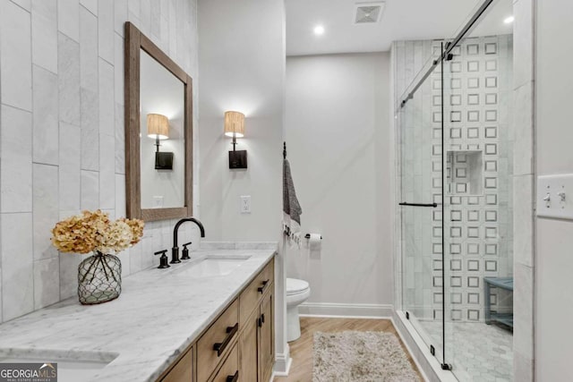 bathroom featuring toilet, vanity, wood-type flooring, and walk in shower