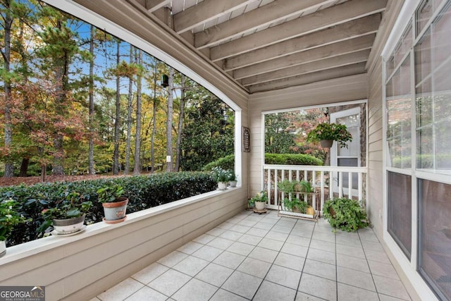 unfurnished sunroom featuring beamed ceiling