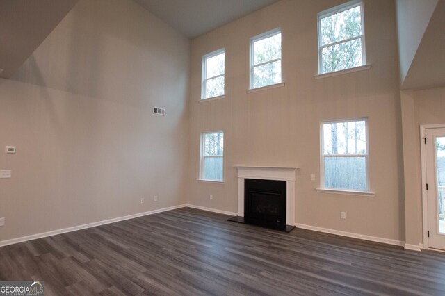 unfurnished living room featuring dark wood-type flooring and high vaulted ceiling