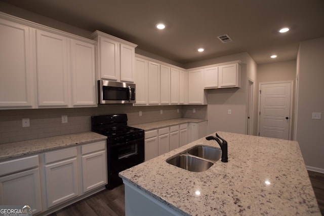 kitchen with black stove, sink, and white cabinets