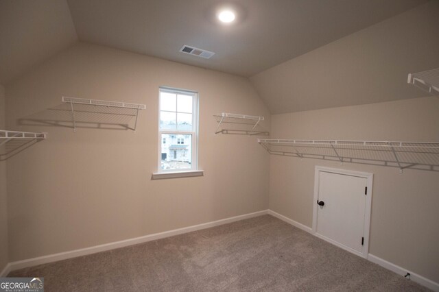 walk in closet with carpet and vaulted ceiling