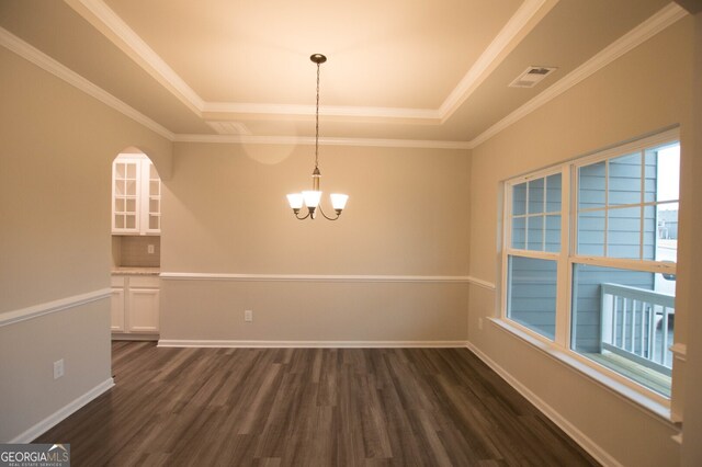 unfurnished dining area featuring an inviting chandelier, ornamental molding, a tray ceiling, and dark wood-type flooring