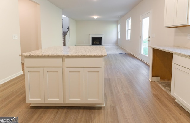 530 River Run Dr Unit 58, Dallas, GA 30132 - kitchen featuring light wood-style floors, a fireplace, light stone countertops, white cabinets, and baseboards