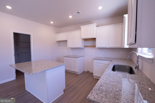 530 River Run Dr Unit 58, Dallas, GA 30132 - kitchen with a sink, wood finished floors, light stone countertops, a kitchen island, and white cabinetry
