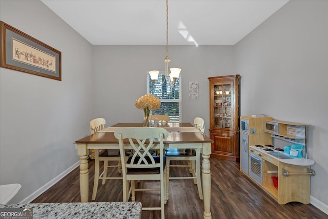 dining room with dark wood-type flooring and a notable chandelier