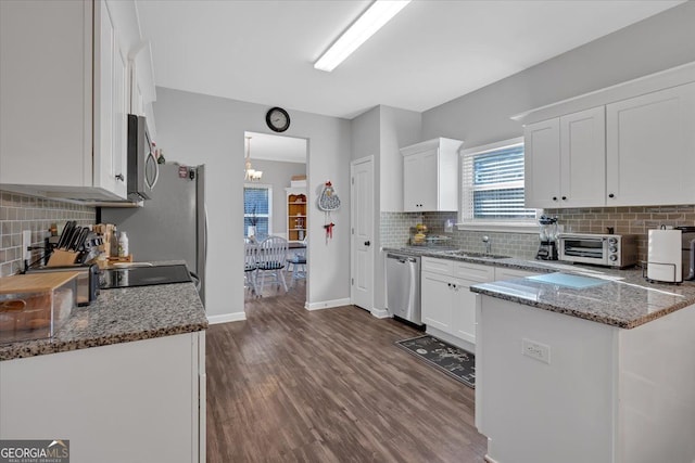 kitchen with white cabinets, dark stone countertops, dark wood-type flooring, and appliances with stainless steel finishes