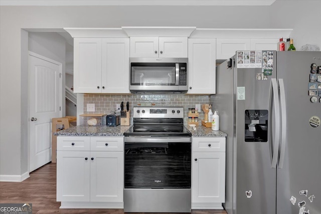 kitchen with white cabinets, dark hardwood / wood-style floors, light stone countertops, and stainless steel appliances