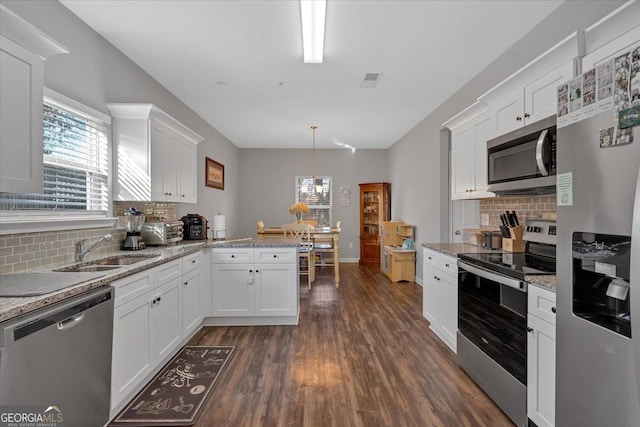 kitchen with decorative backsplash, appliances with stainless steel finishes, sink, decorative light fixtures, and white cabinets