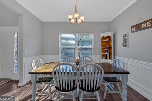 dining space with dark hardwood / wood-style flooring, ornamental molding, and a notable chandelier