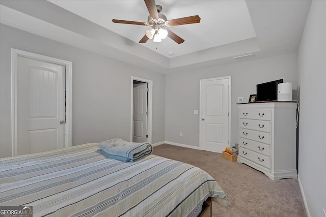 bedroom featuring ceiling fan, a raised ceiling, and light carpet