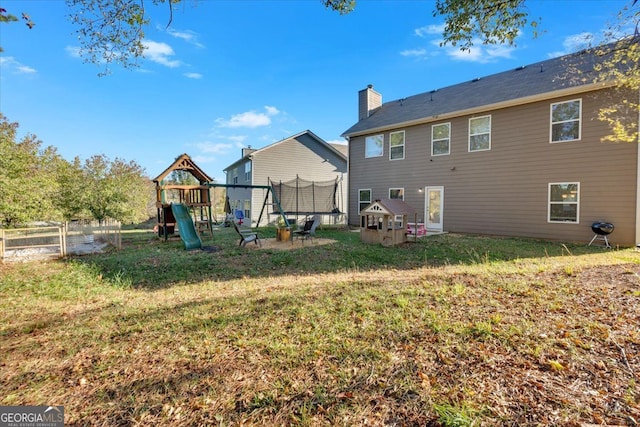 rear view of house featuring a yard, a trampoline, and a playground