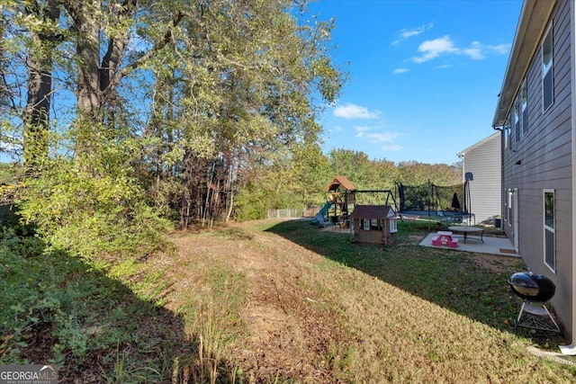 view of yard featuring a playground, a trampoline, and a patio area