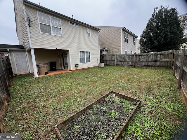 rear view of property featuring central AC unit, a yard, and a patio area